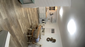 A dining area with a high ceiling, a chandelier, and a wall-mounted sign with motivational phrases. - Lower County Bunk House (Dennis)