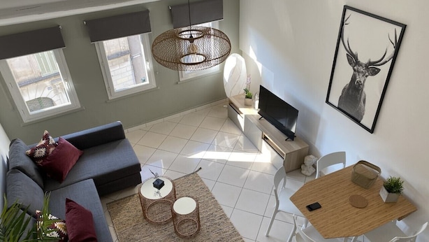 A modern living room with a sofa, two round tables, a dining table, and a television. - APPART NOE - rue Carreterie - 4 pers. (Avignon)