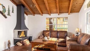 A cozy living room with a fireplace, leather sofas, and a wooden ceiling. - Cute Cozy Cabin- View of the Slopes-Pets OK! (Big Bear Lake)