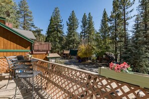 Une terrasse en bois avec des sièges d’extérieur, entourée de grands pins.