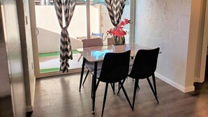 A dining area with a glass table, black chairs, a vase with flowers, and chevron-patterned curtains. - Condo *Zen* King N. Phoenix 30 (Phoenix)