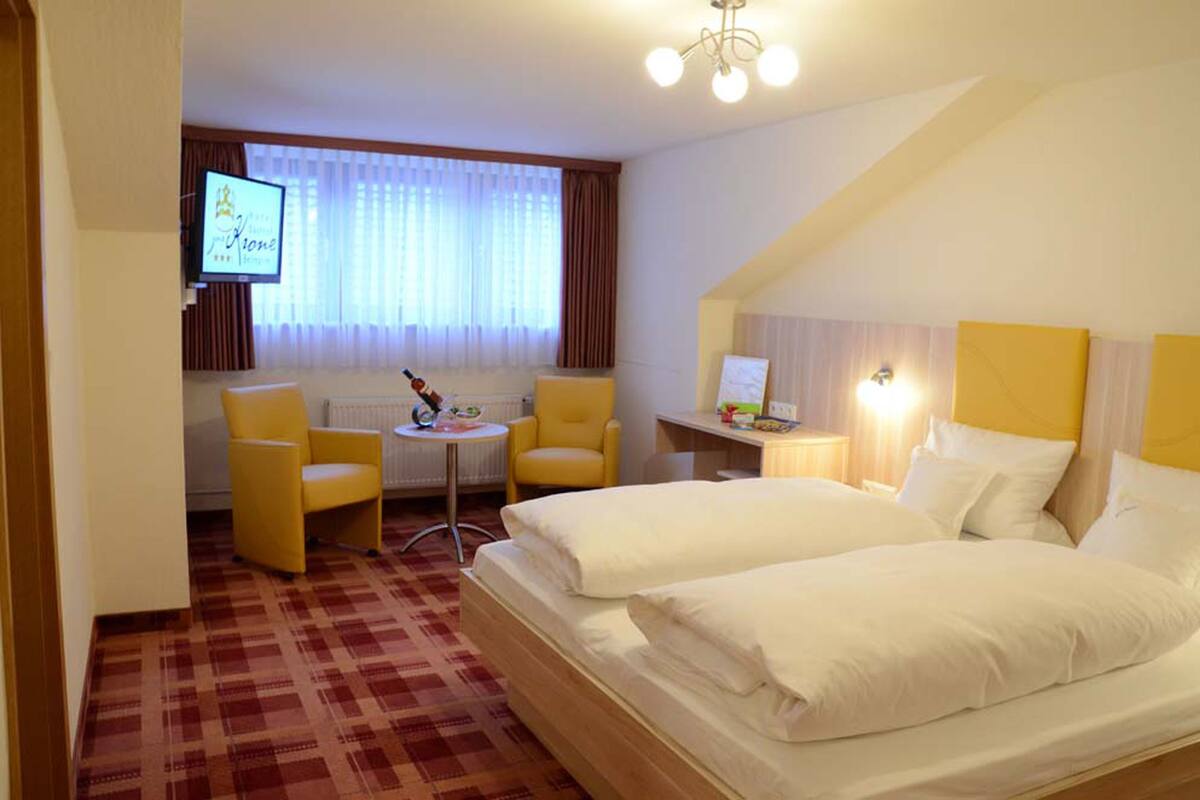 Habitación de hotel con dos camas, televisión, una mesita y una silla.