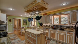 A spacious kitchen with wooden cabinets, granite countertops, and a central island. - Secluded home on 24 acres (Hayesville)