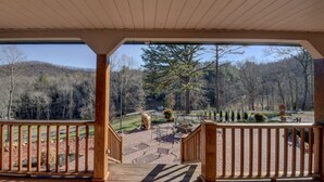 A covered outdoor area with a wooden deck, a stone pathway, and a view of a forested landscape. - Secluded home on 24 acres (Hayesville)