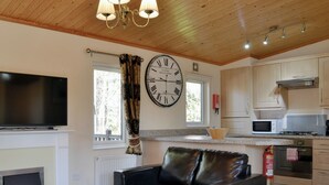A modern living room with a fireplace, a black leather sofa, a wooden coffee table, and a large wall clock.