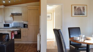 A kitchen with wooden cabinets, a microwave, and a gas stove. There is a dining area with a table and chairs.