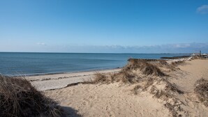 A sandy beach with a clear blue sky and calm sea.