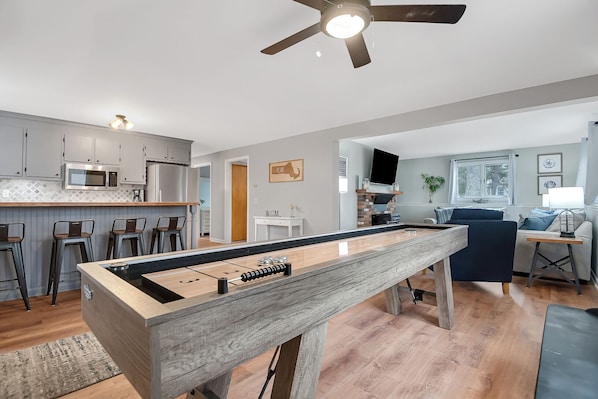 A modern living space with a foosball table, kitchen area, and seating area.