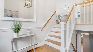 A staircase with white railings and wooden steps leading to a landing. A small table with a plant and a bird sculpture is placed on the landing.