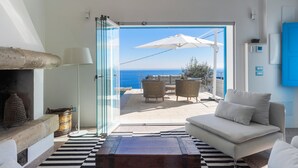 Un soggiorno moderno con una porta vetrata che dà su un balcone con vista sul mare.