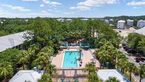 Um resort com piscina central rodeada por palmeiras e espreguiçadeiras.