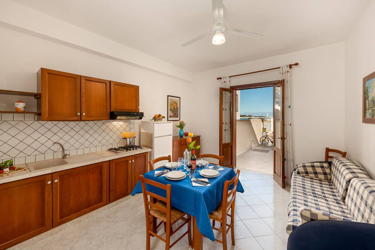 Een compacte keuken met houten kastjes, een eettafel voor vier personen en een balkon met een fiets.