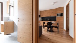 A modern kitchen with wooden cabinets, a black countertop, and a dining area with a round table and chairs. - Al Forte 6 - One Bedroom Apartment, Sleeps 3 (Valdisotto)