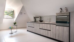 Una cocina moderna con una isla grande, electrodomésticos integrados y una mesita auxiliar con una planta.