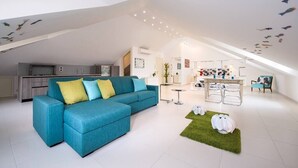 Un espacio habitable moderno con un sofá modular, un comedor y una cocina.