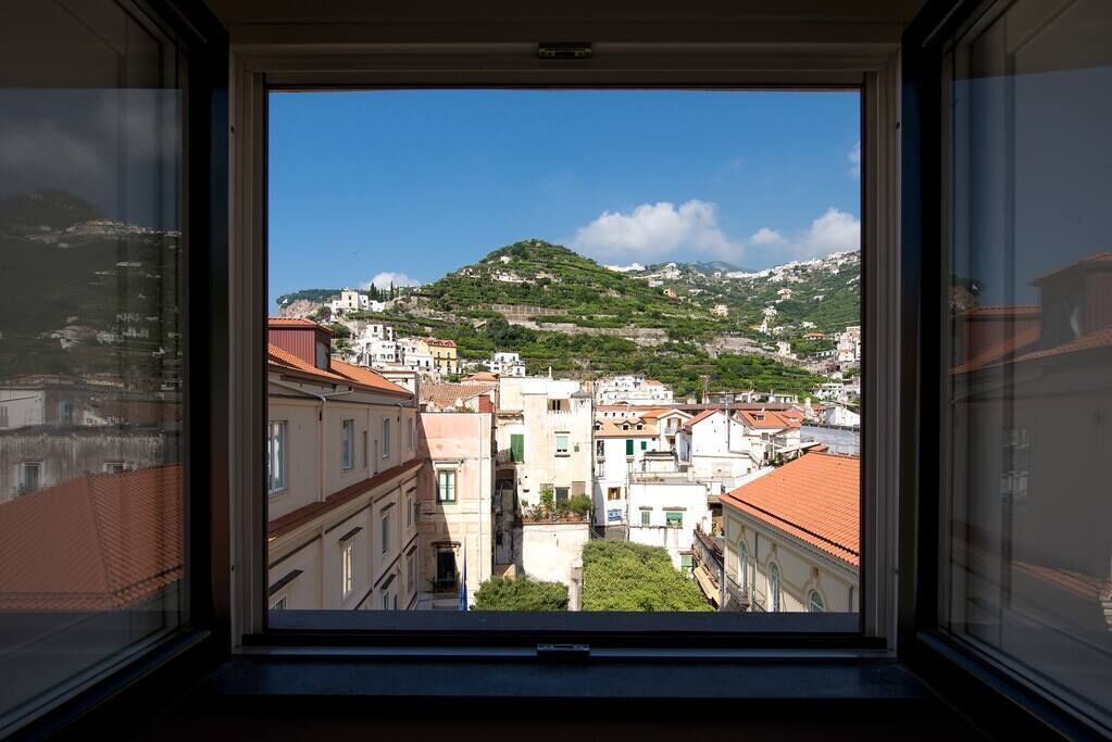 Une vue depuis une fenêtre donnant sur une colline parsemée de bâtiments.