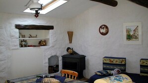 Ein gemütlicher Raum mit Kamin, einem Tisch mit kariertem Tischläufer, einer Holzkiste und einem Regal mit Dekoration.