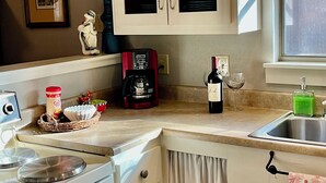 A kitchen with a stove, coffee maker, wine bottle, and a sink. - Cozy & Convenient, 1/2 block off Main St. in Boerne, WALK EVERYWHERE! (Boerne)