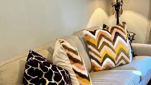 A sofa with three patterned pillows and a wall-mounted lamp. - Cozy & Convenient, 1/2 block off Main St. in Boerne, WALK EVERYWHERE! (Boerne)