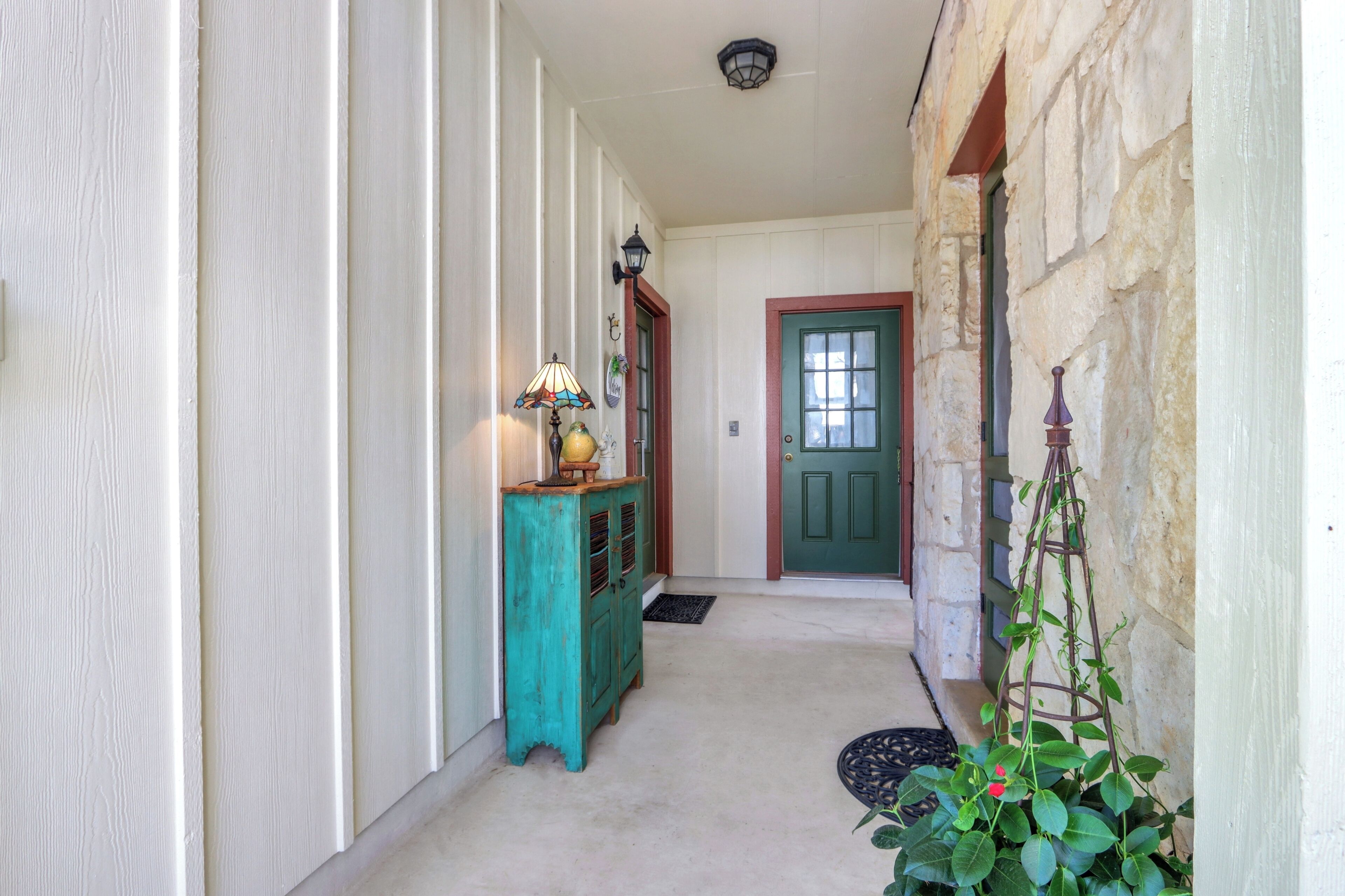 Un couloir avec une armoire de couleur turquoise, une lampe, une porte et une plante grimpante.