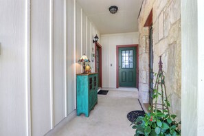 A hallway with a teal cabinet, a lamp, a door, and a climbing plant.