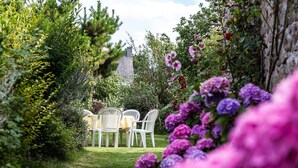 A garden with a table and chairs, surrounded by lush greenery and flowers. - Appartement "kerouac", Maison du 18ème Avec Wifi, Proche des Plages de Sable fin (Carnac)