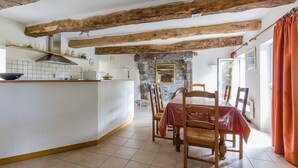 A rustic kitchen with exposed wooden beams, a stone fireplace, and a dining area with a table and chairs. - Appartement "kerouac", Maison du 18ème Avec Wifi, Proche des Plages de Sable fin (Carnac)