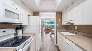 Eine moderne Küche mit weißen Geräten, ein Essbereich mit Aussicht und ein Deckenventilator.
