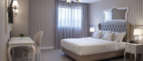 A neatly arranged bedroom with a bed, bedside tables, a desk, and a chair.