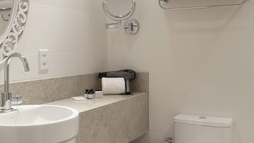 Un baño moderno con lavabo blanco, espejo, inodoro y toallero.