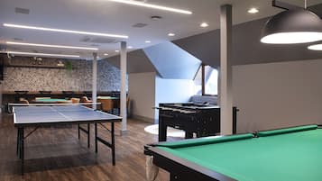 A billiards room with a pool table, a foosball table, and a ping pong table.
