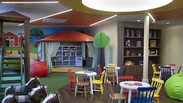 Children can play and dine at this vibrant playroom featuring a farm-themed mural and comfortable seating options.