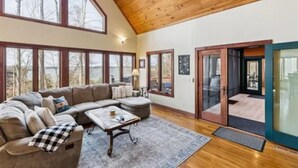 A spacious living room with a large sectional sofa, a coffee table, and a view through large windows.