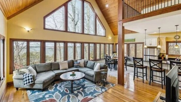 A spacious living area with a large sectional sofa, a round coffee table, and a view of the outdoors through large windows.