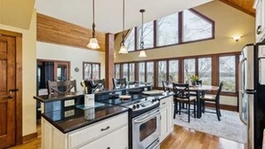 A kitchen with a stove, oven, and dining area with chairs and a table.