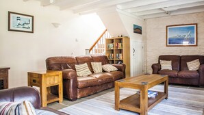 A cozy living room with a brown leather sofa, a wooden coffee table, and striped area rugs. - 3 bedroom accommodation in Boscastle (Boscastle)