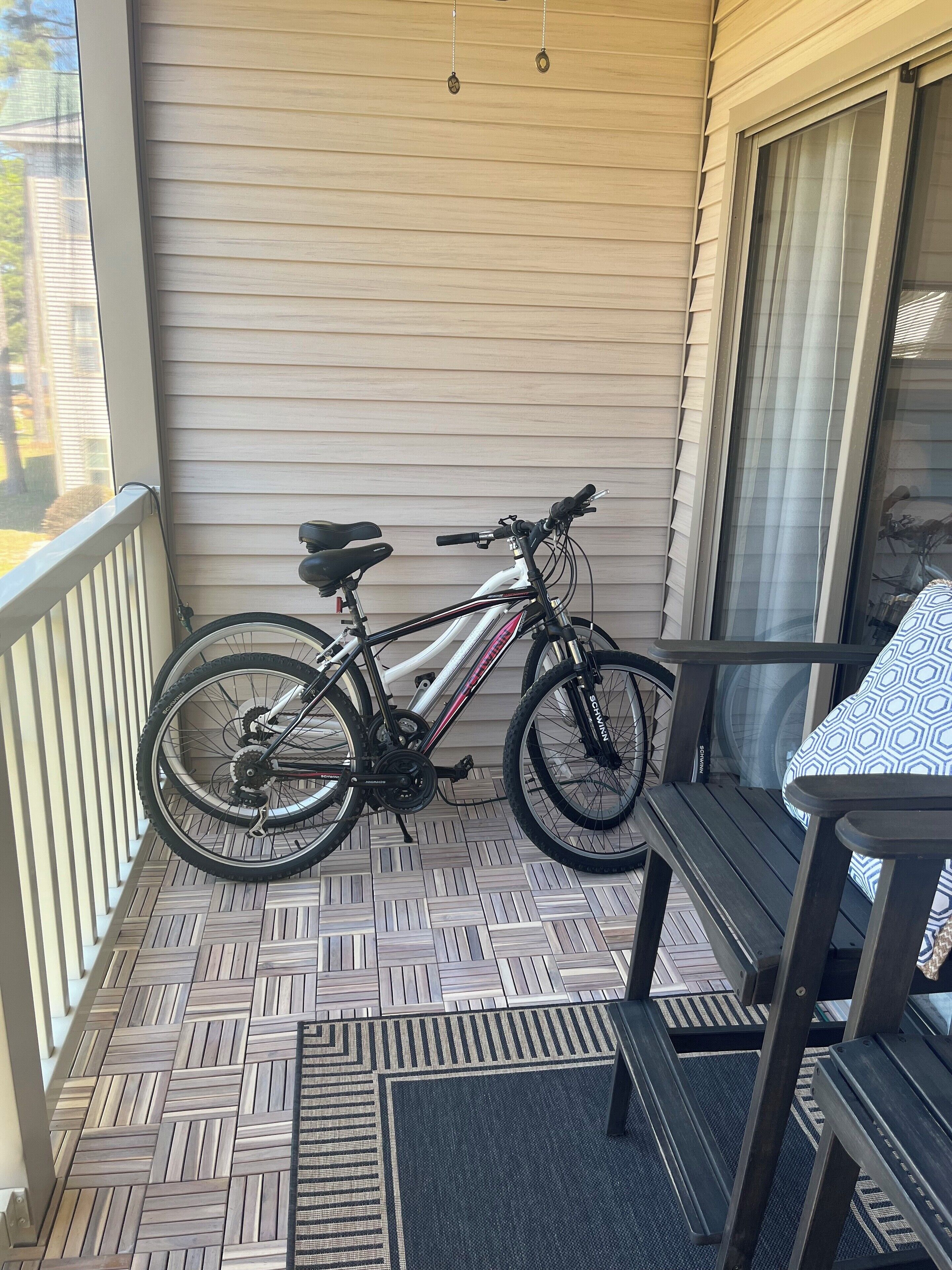 A bicycle parked on a wooden deck with a table and chairs nearby.