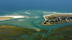 Vue aérienne d’une zone côtière comprenant une plage, un port de plaisance et des immeubles résidentiels.