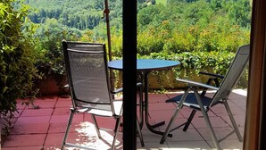 Un patio con due sedie, un tavolo e un ombrellone rosso.