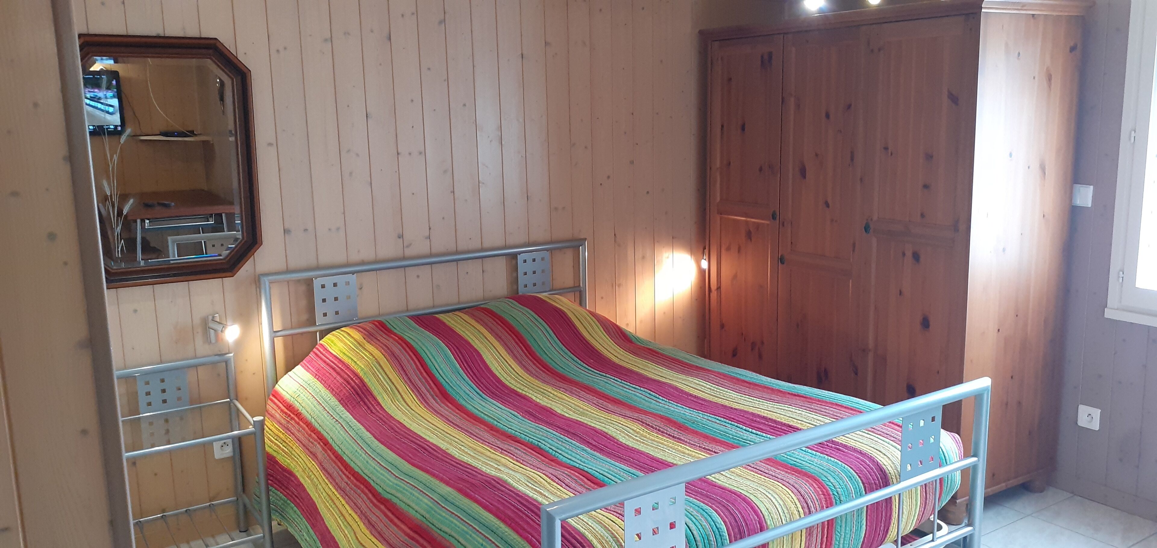 Une chambre à coucher avec un lit, une armoire et un miroir.