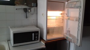 Una cocina compacta con microondas y refrigerador abierto.