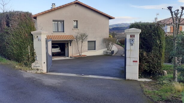 Una casa de dos pisos con entrada de garaje, un pequeño jardín y vistas del paisaje circundante.