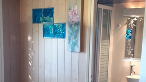 Una habitación con paneles de madera, una pequeña mesa, una silla y una ventana con persianas.