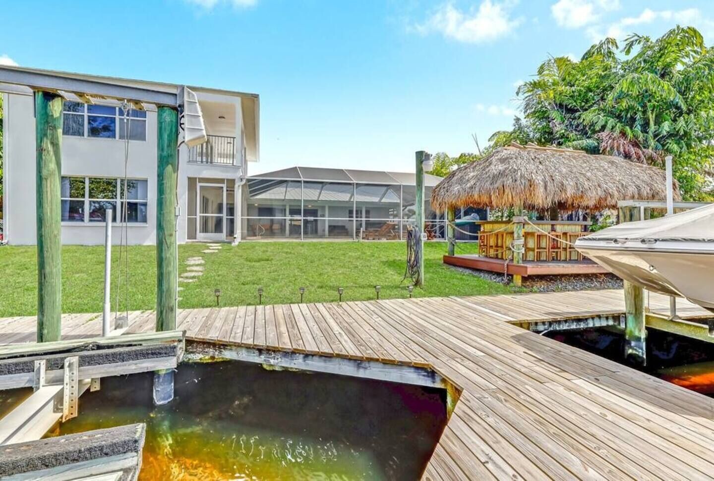 Ein Resort mit einer Holzterrasse, einem Pool, einer strohgedeckten Hütte und einem modernen Gebäude mit großen Fenstern.