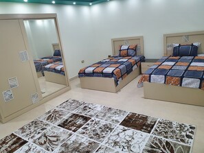 A bedroom with three beds, a large mirror, and a patterned rug. - Lovely 3-bed Pyramids Viewapartment in Kafr Nassar (Giza)