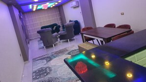 A modern dining area with a long table and chairs, a patterned rug, and a ceiling with recessed lighting and decorative elements. - Lovely 3-bed Pyramids Viewapartment in Kafr Nassar (Giza)