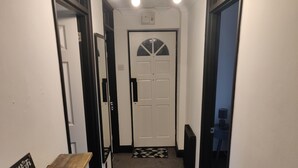 A hallway with a wooden bench, a door with a frosted glass window, and a black and white patterned rug. - Riverside Park Penthouse Apartment in St Neots (Eaton Ford)