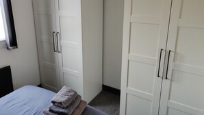 A bedroom with a bed, a wardrobe, and a hanging light fixture. - Riverside Park Penthouse Apartment in St Neots (Eaton Ford)