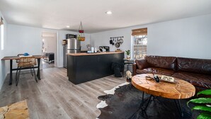 Un espacio moderno con una isla de cocina, un sofá de cuero y una mesa de centro redonda.