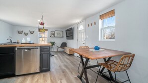 Una cocina moderna con lavavajillas, suelo de madera y un comedor con mesa y sillas.